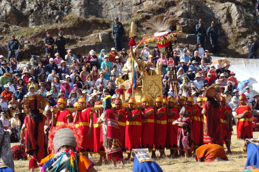 The Inca carried on a golden litter during the Inti Raymi re-enactment at Sacsayhuamán, surrounded by performers in red