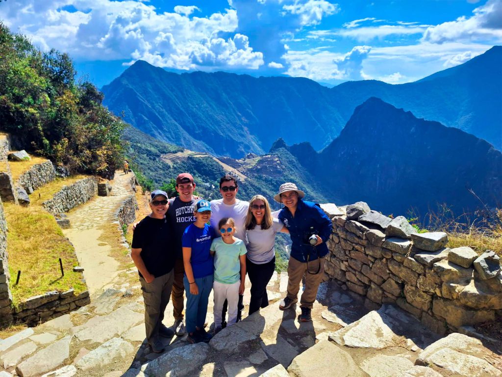 Family of hikers of different ages posing at the Sun Gate above Machu Picchu