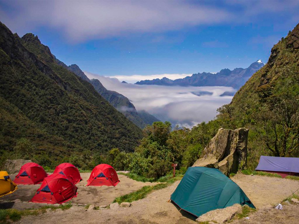 Tents at Pacaymayo campsite on the Inca Trail with clouds below the mountains