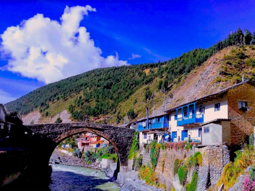 Inca Trail in July 2027: Weather, the Busiest Week and How to Plan Around It 2 Colonial stone bridge over the river in Paucartambo, with white houses with blue balconies