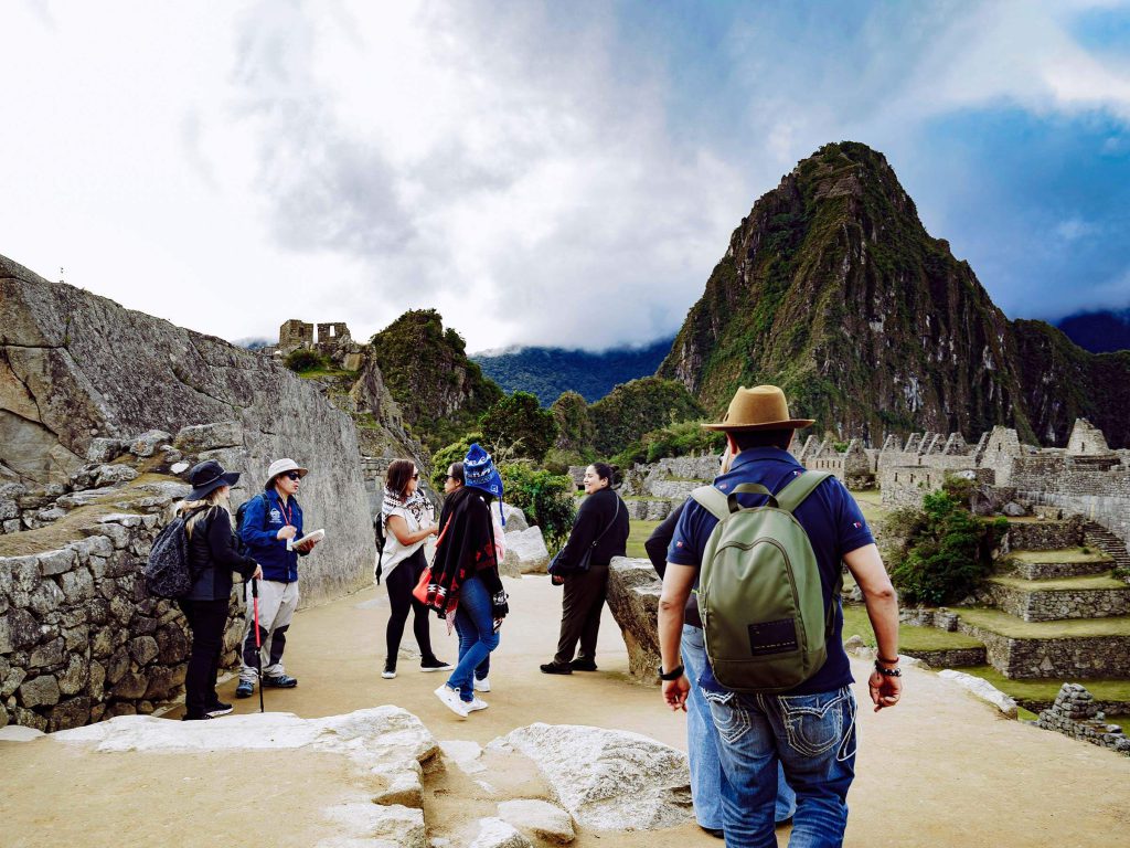 Machu Picchu Tickets 2027: Prices, When They Go on Sale and How to Buy 1 A guided group walking through the Machu Picchu citadel with Huayna Picchu mountain behind