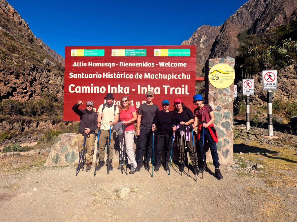 Group of hikers at the Km 82 welcome sign of the Inca Trail in the Historic Sanctuary of Machu Picchu