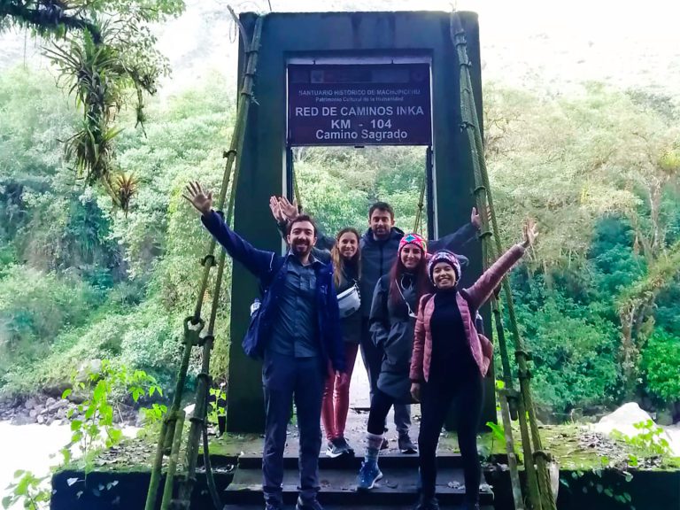 Group of hikers at the Km 104 bridge with the sign of the Inca Road Network, Red de Caminos Inka