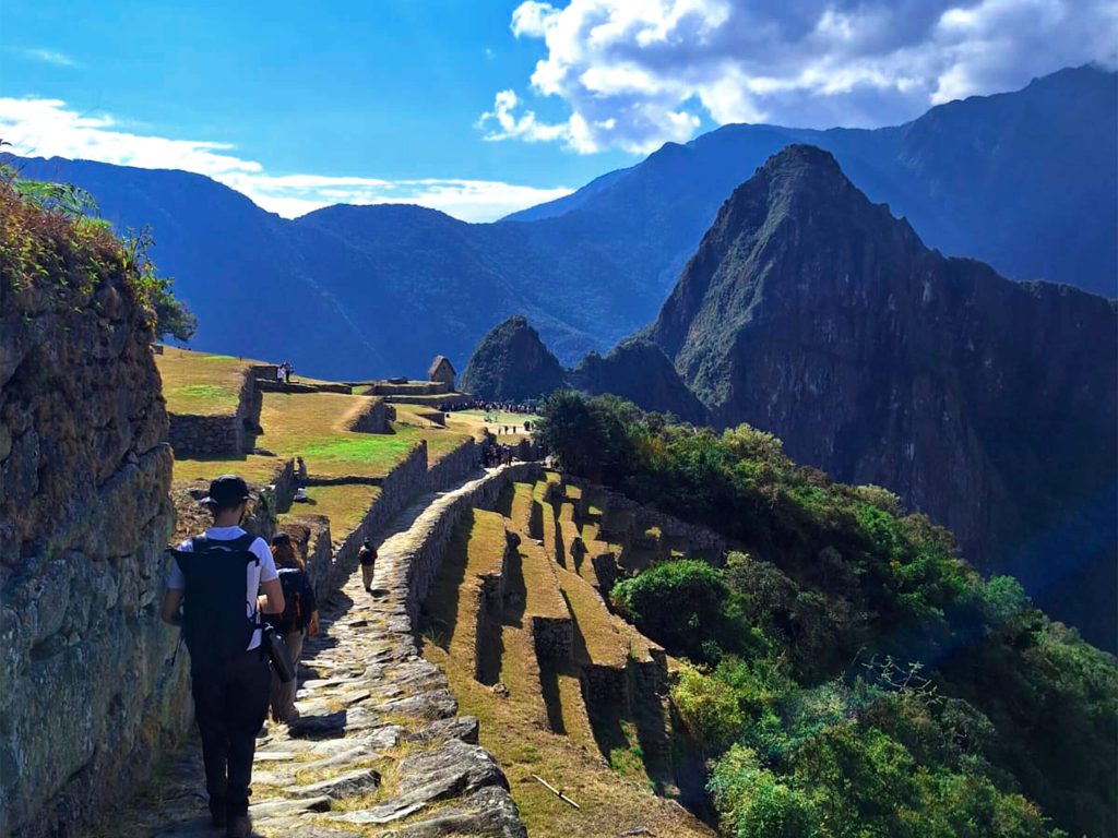 No dejar rastro en el Camino Inca: las normas oficiales y qué puedes hacer tú 2 Caminante en un sendero inca de piedra sobre los andenes de Machu Picchu con el Huayna Picchu detrás
