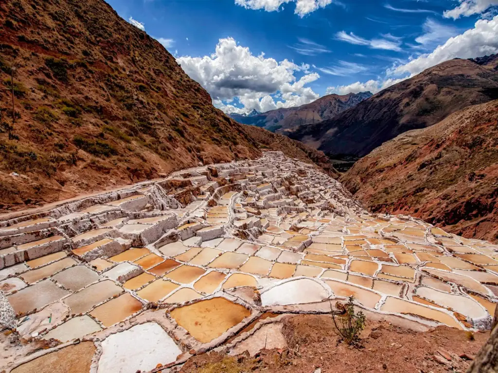 Sacred Valley of Peru: Map, What to See, Tickets and Altitude 3 Maras salt pans on a hillside in the Sacred Valley, with mountains behind