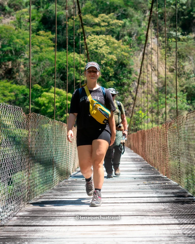 Hiker crossing a hanging bridge with wire sides on the Inca Jungle trek