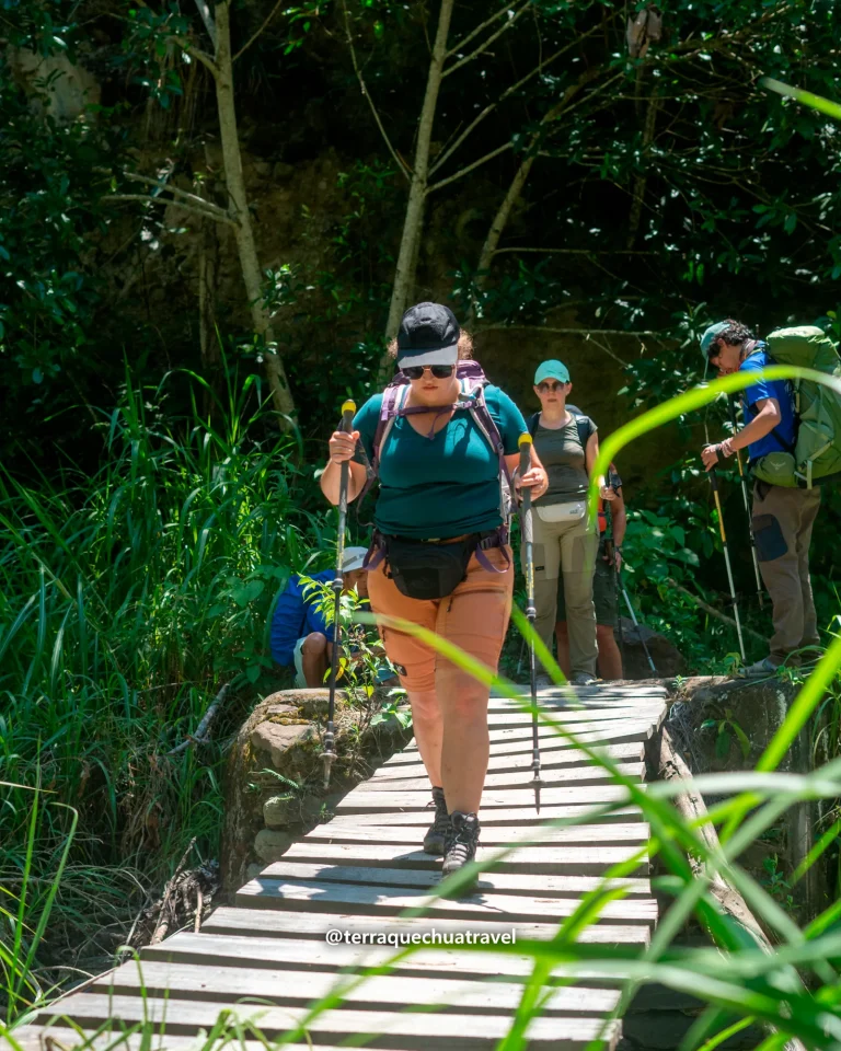 Hikers crossing a wooden footbridge on the Inca Jungle trek