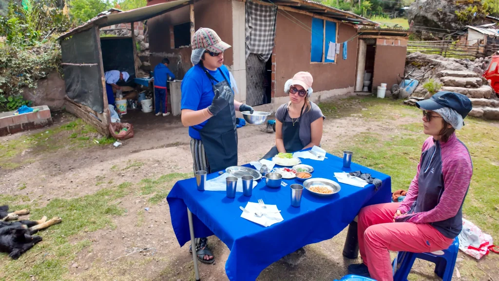 Hikers served lunch at an outdoor table beside a rural home on the Lares trek