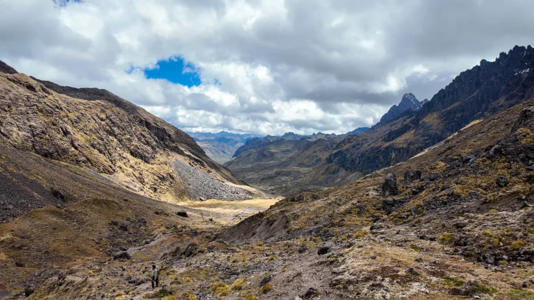 Rocky slopes and a glacial valley under clouds on the Lares trek