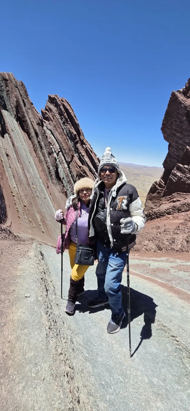 Couple with trekking poles on the trail between the striped rock fins of Pallay Punchu