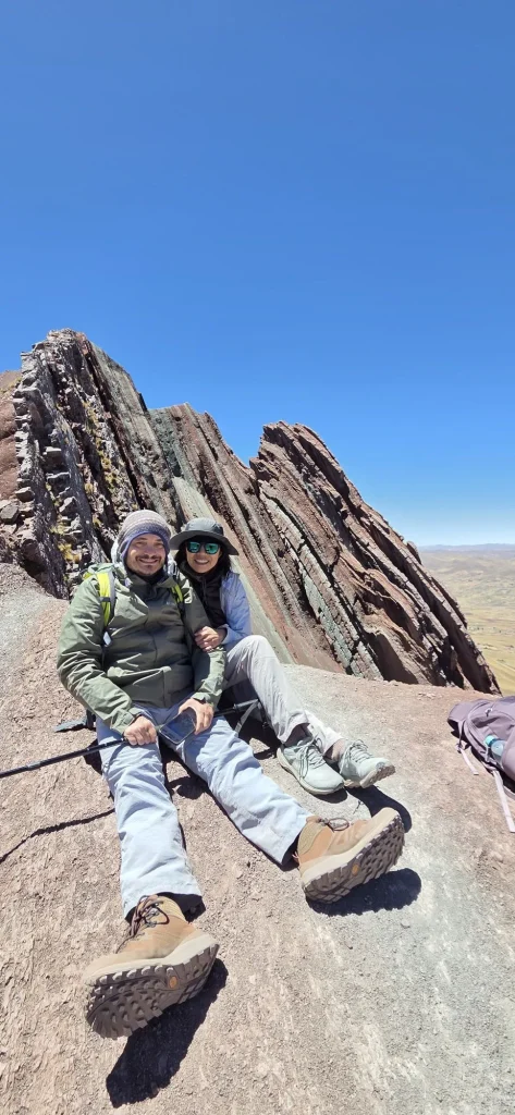 Two hikers resting below the tilted rock fins of Pallay Punchu