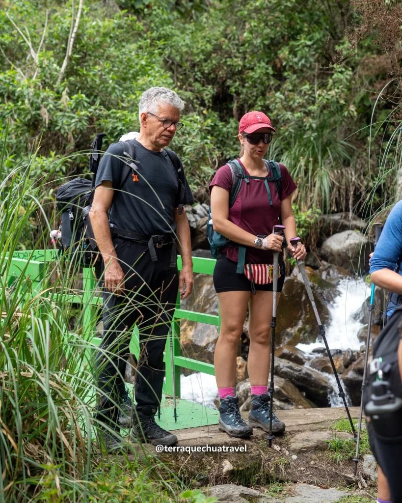 Inca Trail vs Salkantay Trek: Which Is Better for You? 2 Two hikers on a wooden bridge beside a waterfall in the cloud forest on the Salkantay trek