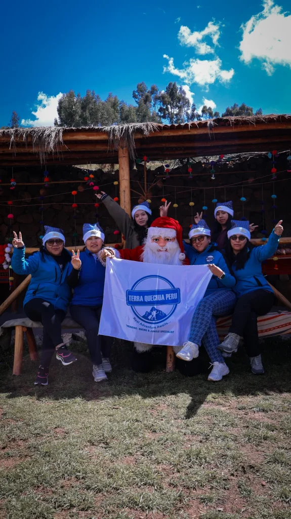 Social Projects 2 Terra Quechua team in Christmas hats with Santa Claus and the company banner at a Christmas chocolatada
